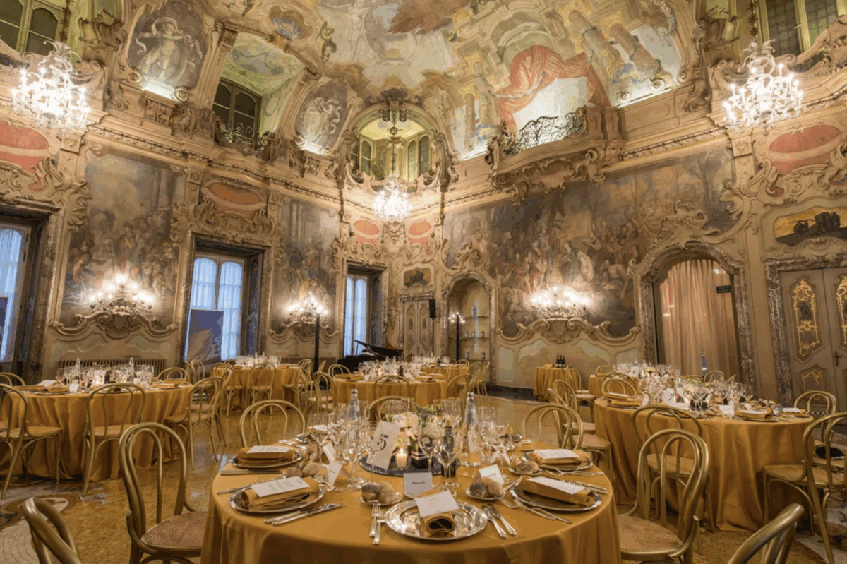 Sala affrescata con tavoli rotondi apparecchiati per evento formale