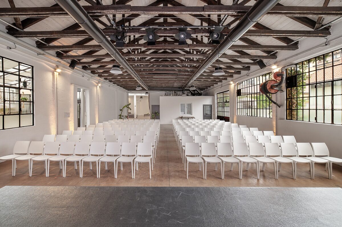 platea allestita con sedie bianche e grandi finestre vetrate ad illuminare la sala